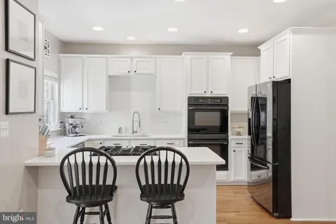 a kitchen with stainless steel appliances a refrigerator a sink a stove a dining table and chairs