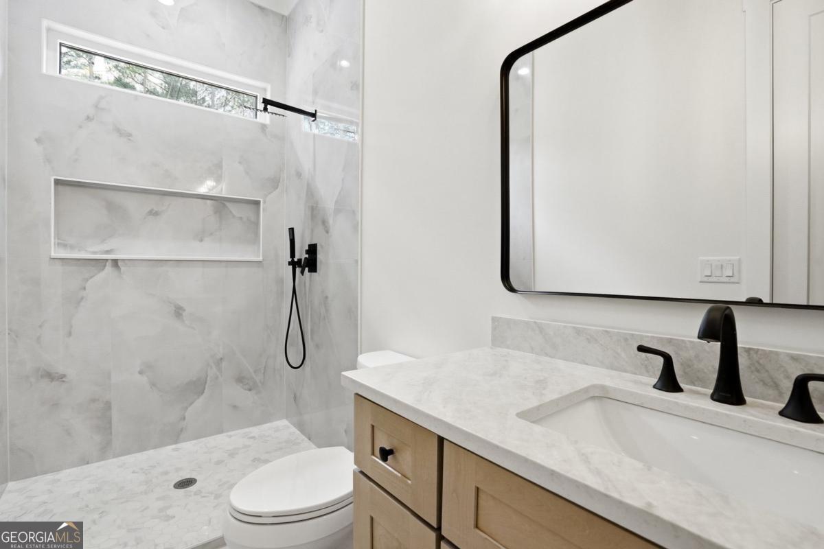 1557 Whitley Road Dacula, GA 30019 - Photo 29 of 46 a bathroom with a granite countertop sink toilet and shower