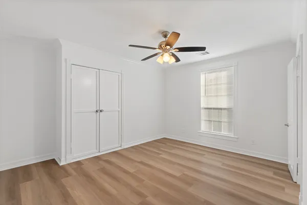 a view of empty room with wooden floor and fan