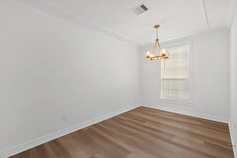 an empty room with a chandelier fan and windows