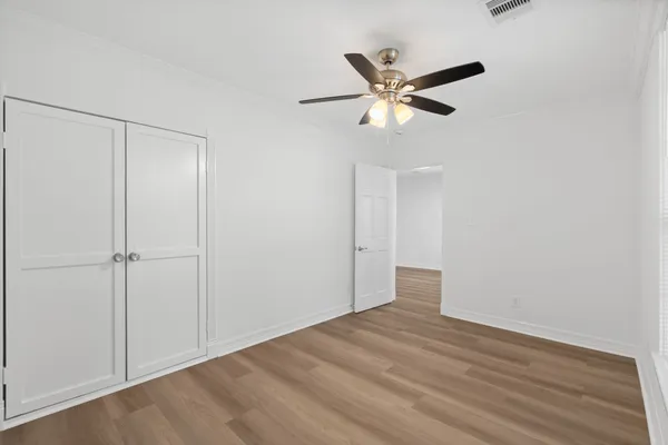 a view of empty room with wooden floor and ceiling fan