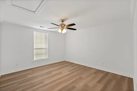 an empty room with wooden floor fan and windows