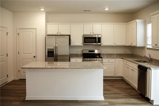 a large kitchen with stainless steel appliances granite countertop a stove a sink and a microwave