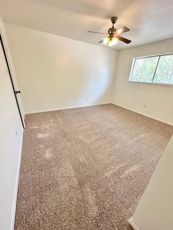 an empty room with windows and fan
