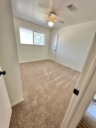 en empty room with windows and ceiling fan