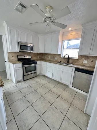 a kitchen with granite countertop a sink cabinets and stainless steel appliances