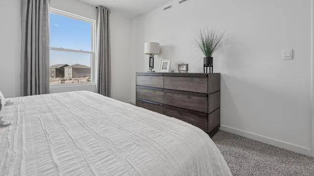 a bedroom with a bed and a potted plant on the dresser