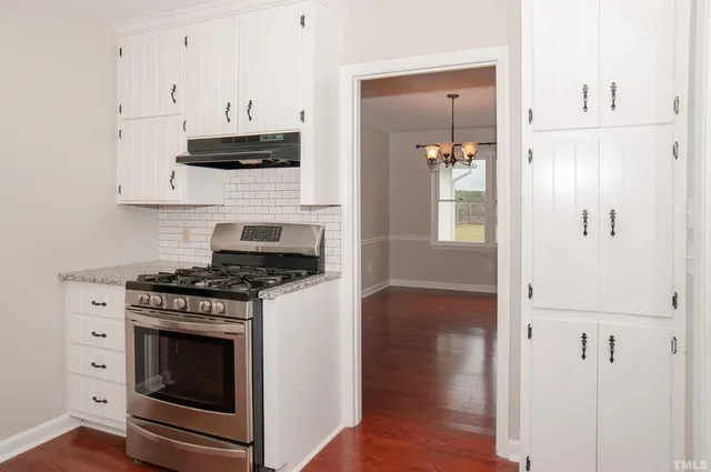 a view of a kitchen with granite countertop white cabinets and window