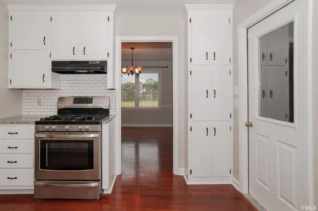 a kitchen with stainless steel appliances white cabinets and wooden floor