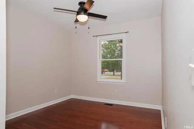 an empty room with wooden floor and ceiling fan