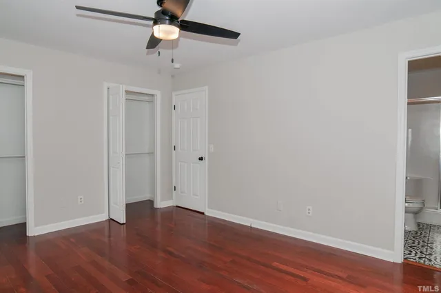 an empty room with wooden floor ceiling fan and window
