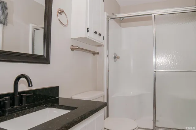 an empty room with wooden floor chandelier fan and windows