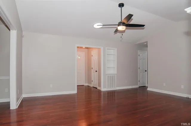 an empty room with wooden floor a fireplace a ceiling fan and wooden floor