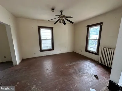 an empty room with windows and ceiling fan
