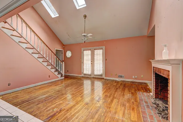 a view of an empty room with wooden floor and a fireplace