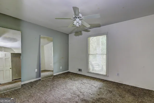 an empty room with closet and a chandelier fan