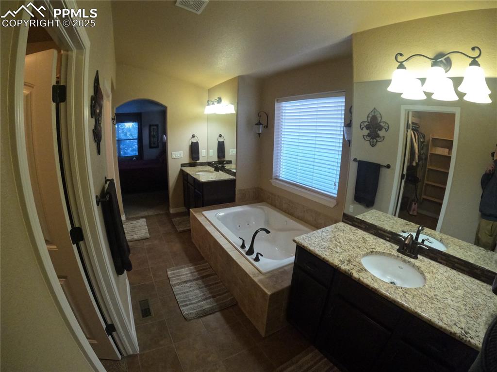 1131 Old North Gate Road Colorado Springs, CO 80921 - Photo 19 of 39 Primary Bathroom with two vanities, a garden tub, a walk in closet, and dark tile patterned flooring