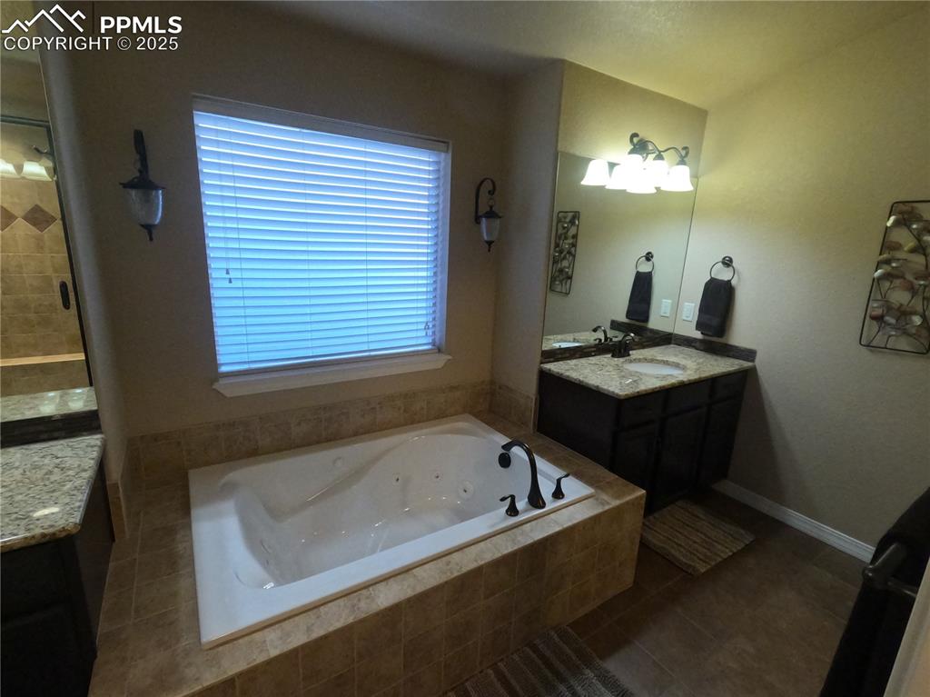 1131 Old North Gate Road Colorado Springs, CO 80921 - Photo 20 of 39 Primary Bathroom featuring tile patterned flooring, vanity, a jetted tub, and a stall shower
