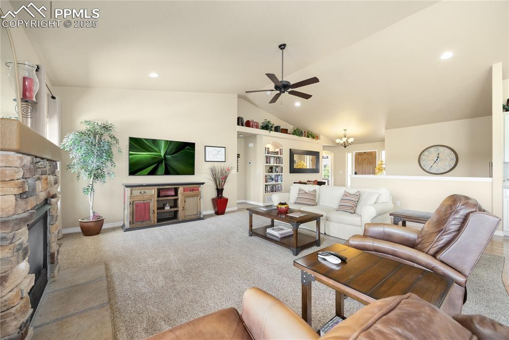 1131 Old North Gate Road Colorado Springs, CO 80921 - Photo 4 of 39 Carpeted living area with ceiling fan, lofted ceiling, a stone fireplace, recessed lighting, and a chandelier