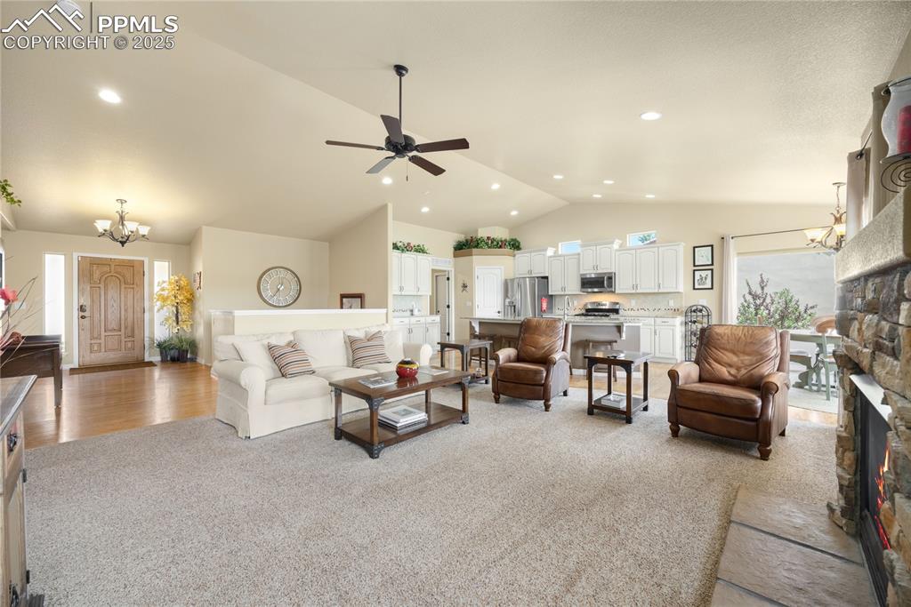 1131 Old North Gate Road Colorado Springs, CO 80921 - Photo 6 of 39 Living area with lofted ceiling, light colored carpet, a stone fireplace, and ceiling fan