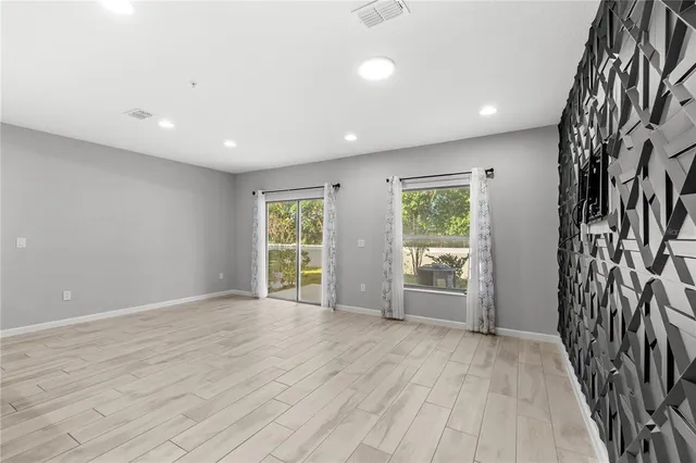 a view of an empty room with a window and wooden floor