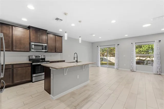 a large kitchen with stainless steel appliances a large counter top a stove a refrigerator and a sink