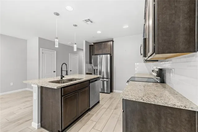 a kitchen with stainless steel appliances granite countertop a sink a stove and a wooden floors