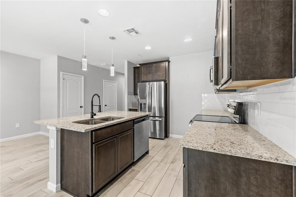 260 Smugglers Way Apopka, FL 32712 - Photo 7 of 34 a kitchen with stainless steel appliances granite countertop a sink a stove and a wooden floors
