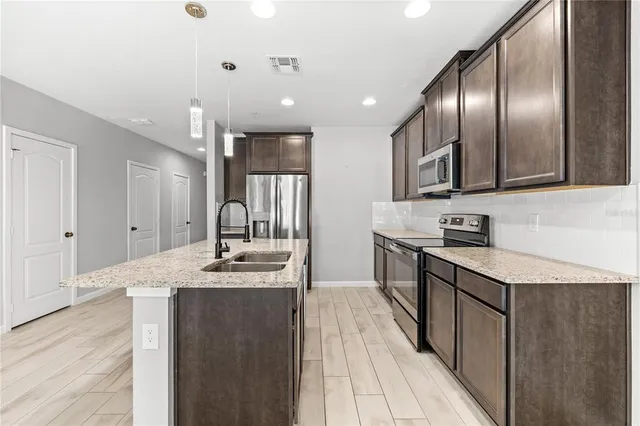 a large kitchen with stainless steel appliances kitchen island granite countertop a stove a sink and a refrigerator