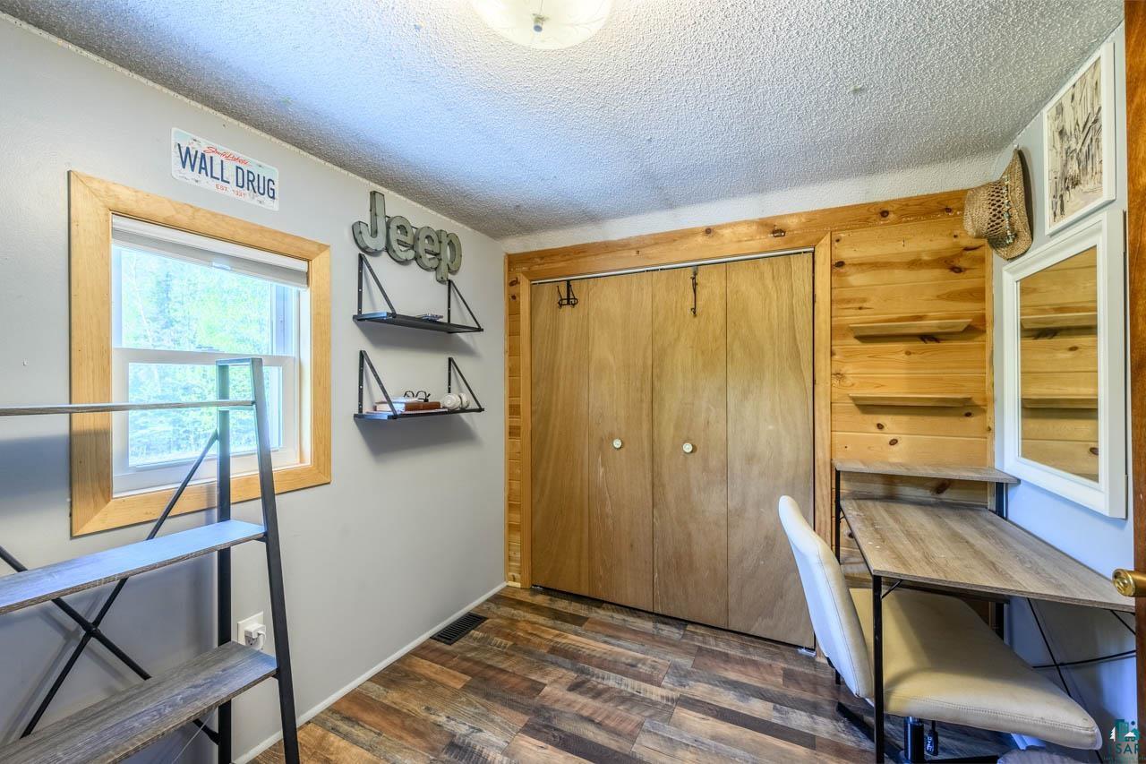 2581 O'Rourke Road Hibbing, MN 55746 - Photo 23 of 61 Room featuring wood-finish flooring, a double-door closet, wood paneling, a built-in desk, and a window with wood trim