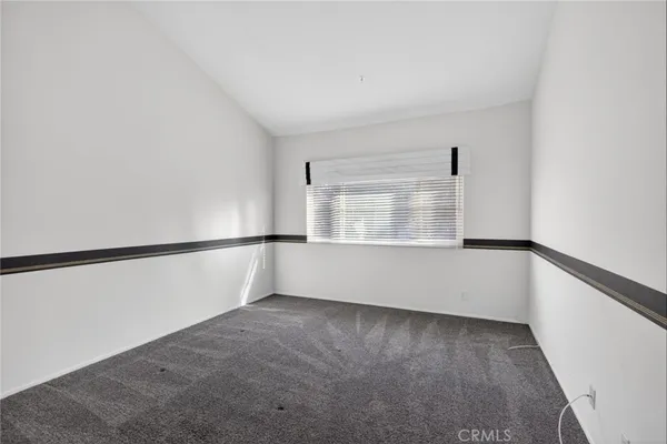 a view of an empty room with wooden floor and windows