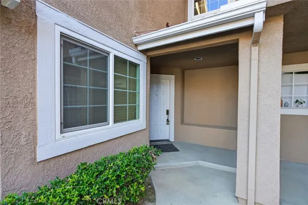 a front view of a house with a large window and potted plants