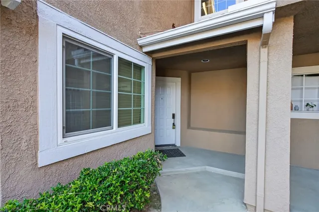 a front view of a house with a large window and potted plants