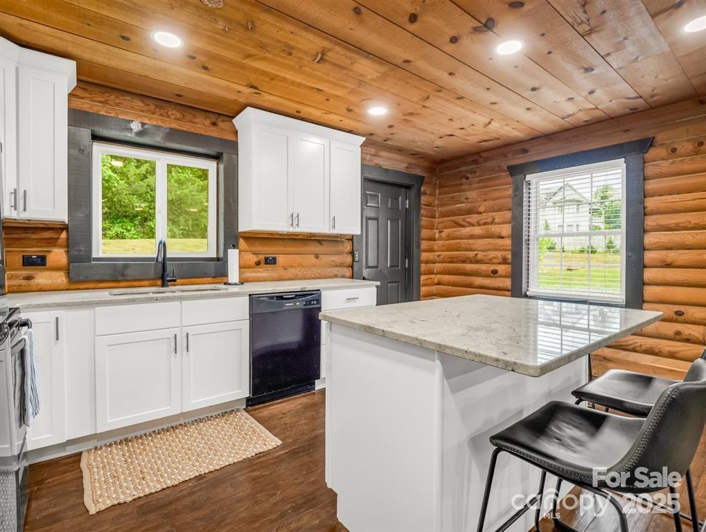 112 Bills Creek Road Lake Lure, NC 28746 - Photo 12 of 42 a kitchen with stainless steel appliances kitchen island granite countertop a stove a sink dishwasher and white cabinets with wooden floor