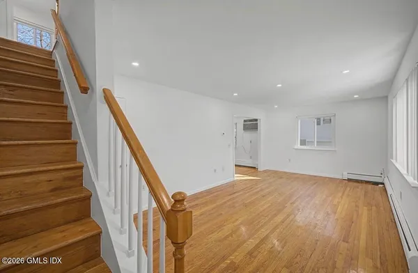a view of an empty room with wooden floor and stairs