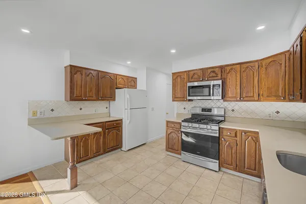 a kitchen with stainless steel appliances granite countertop a stove top oven a sink dishwasher and a refrigerator
