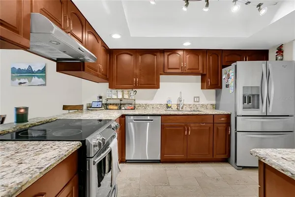 a kitchen with stainless steel appliances granite countertop a sink a stove and a refrigerator