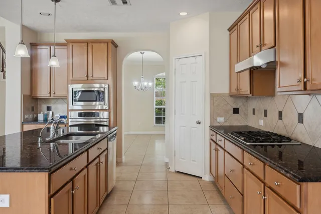 a kitchen with stainless steel appliances granite countertop a sink stove and refrigerator
