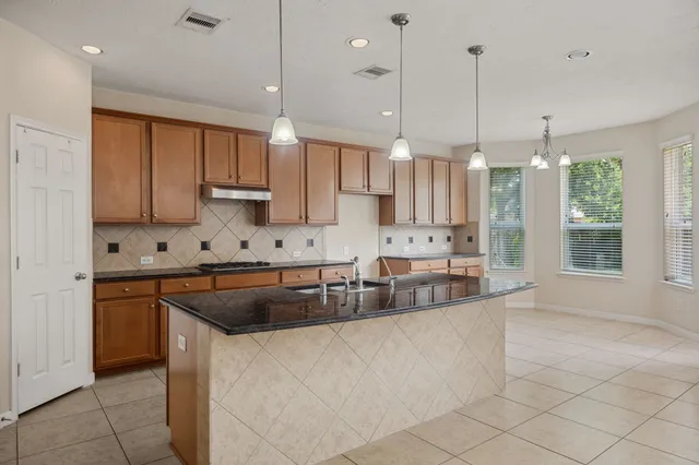 a large kitchen with kitchen island a large counter top stainless steel appliances and cabinets