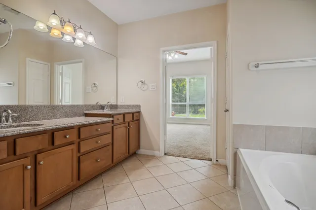 a spacious bathroom with a granite countertop sink a toilet a mirror and a bathtub
