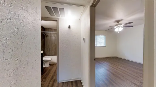 a view of a room with wooden floor a ceiling fan and a bathroom