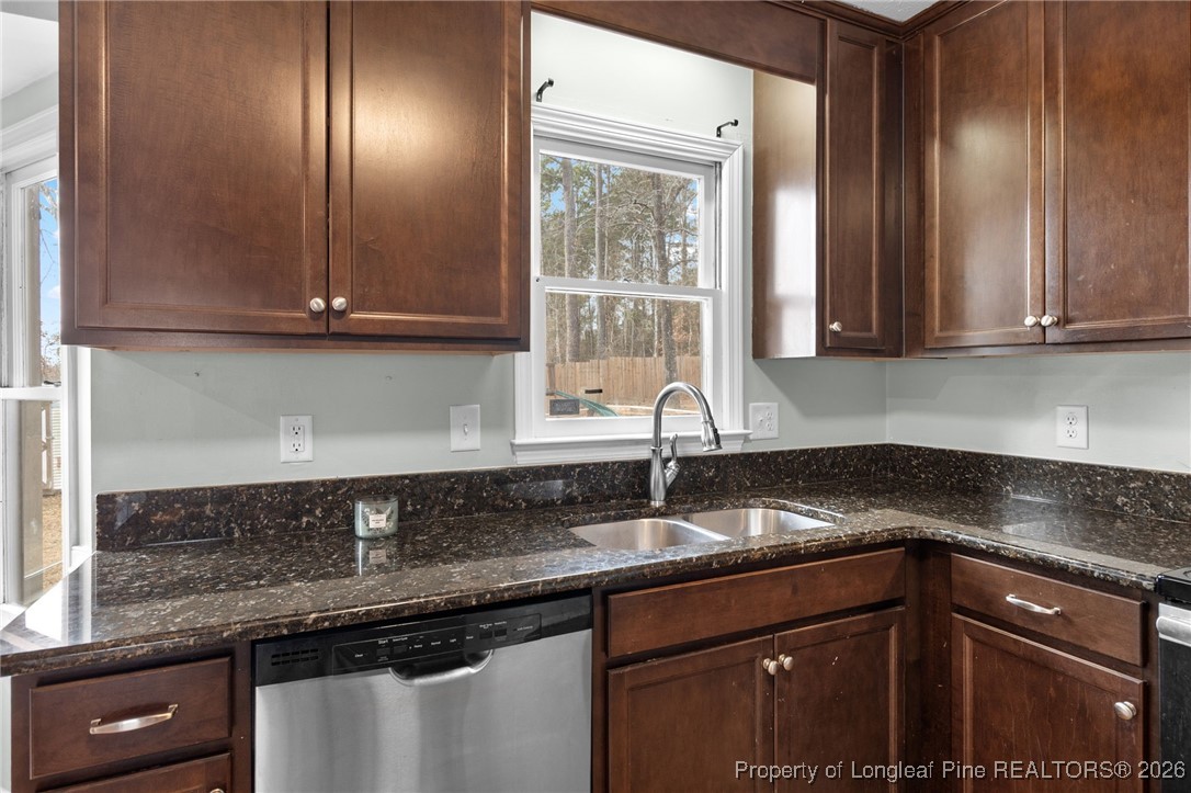 6654 Vaughn Road Fayetteville, NC 28304 - Photo 12 of 36 a kitchen with granite countertop a sink stainless steel appliances white cabinets and a window