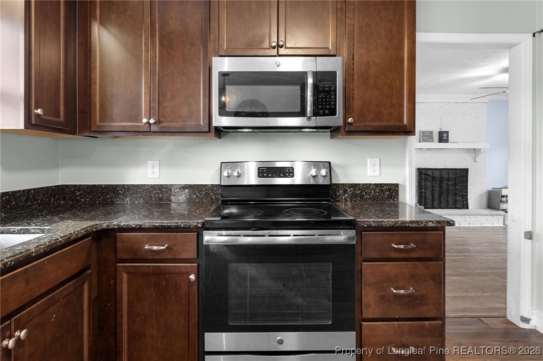 6654 Vaughn Road Fayetteville, NC 28304 - Photo 13 of 36 a kitchen with stainless steel appliances granite countertop a stove top oven microwave and cabinets