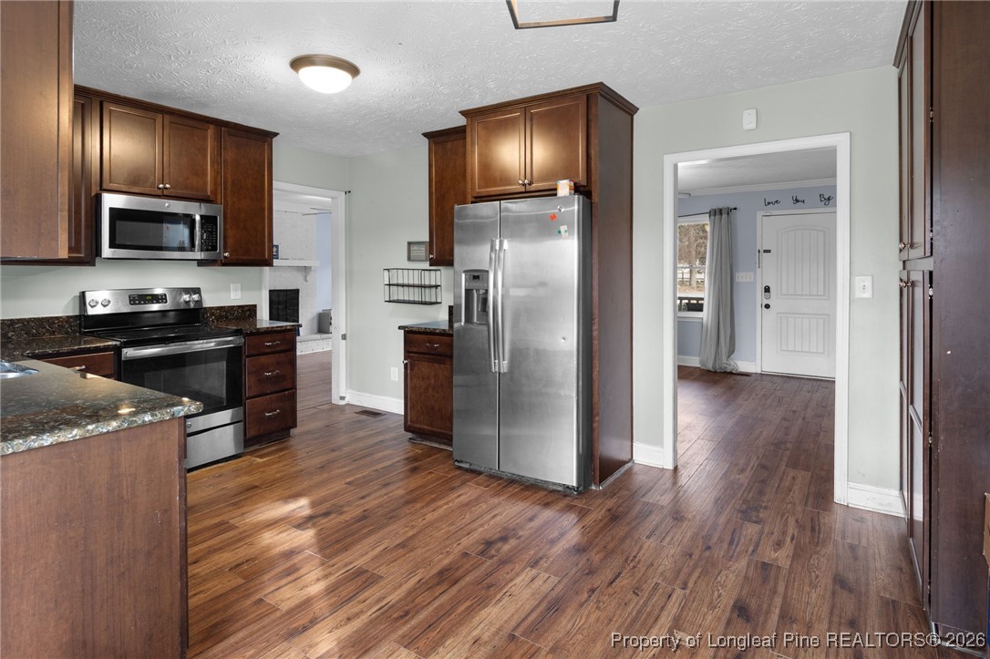 6654 Vaughn Road Fayetteville, NC 28304 - Photo 10 of 36 a kitchen with stainless steel appliances granite countertop a refrigerator a sink a stove and oven with wooden floor