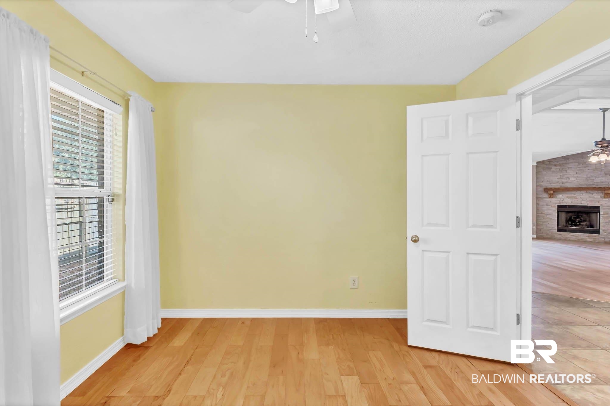 9607 Czar Court Fairhope, AL 36532 - Photo 26 of 42 Empty room featuring a ceiling fan, light wood-style flooring, and a fireplace