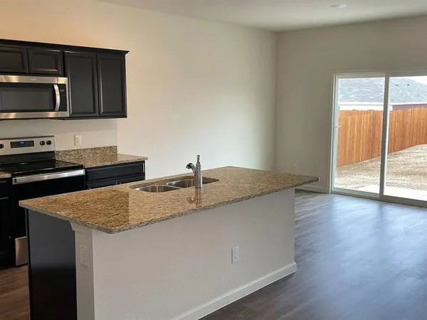 a kitchen with stainless steel appliances granite countertop a sink a microwave cabinets and wooden floor