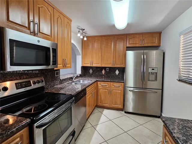a kitchen with granite countertop a refrigerator stove and microwave