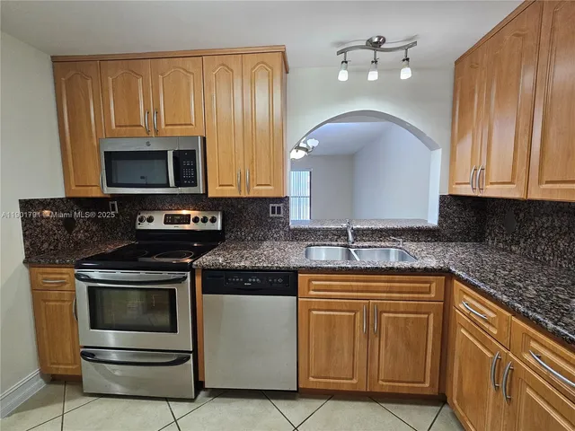 a kitchen with granite countertop a stove sink and microwave