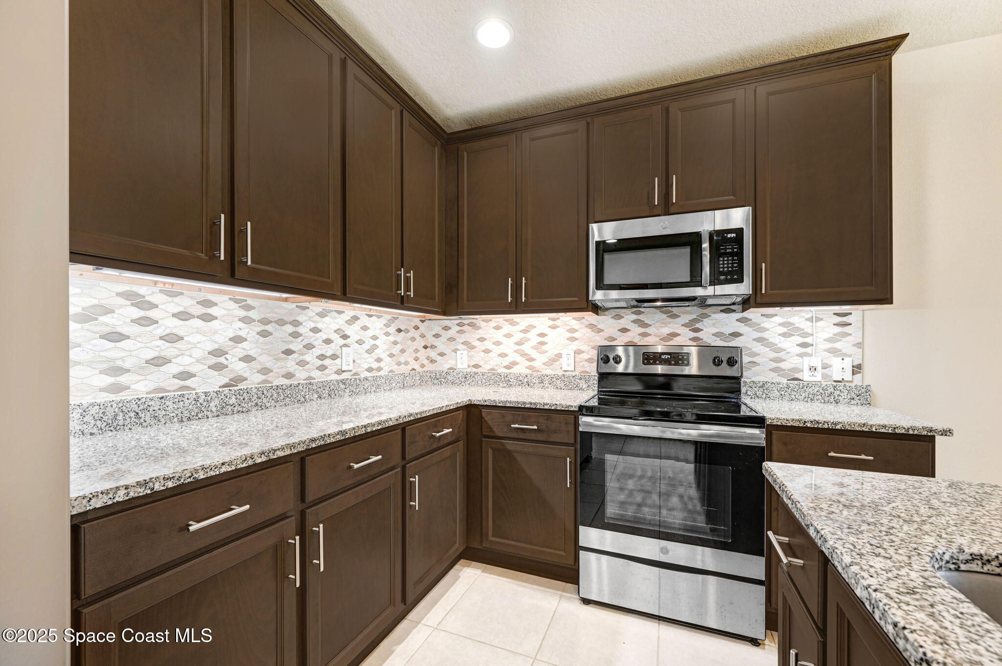 1430 Lara Circle, Unit 103 Rockledge, FL 32955 - Photo 8 of 39 a kitchen with granite countertop wooden cabinets and stainless steel appliances