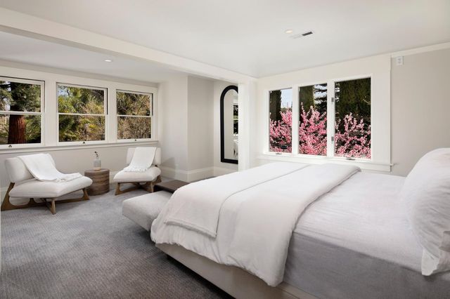 a bedroom with bed couches and large window